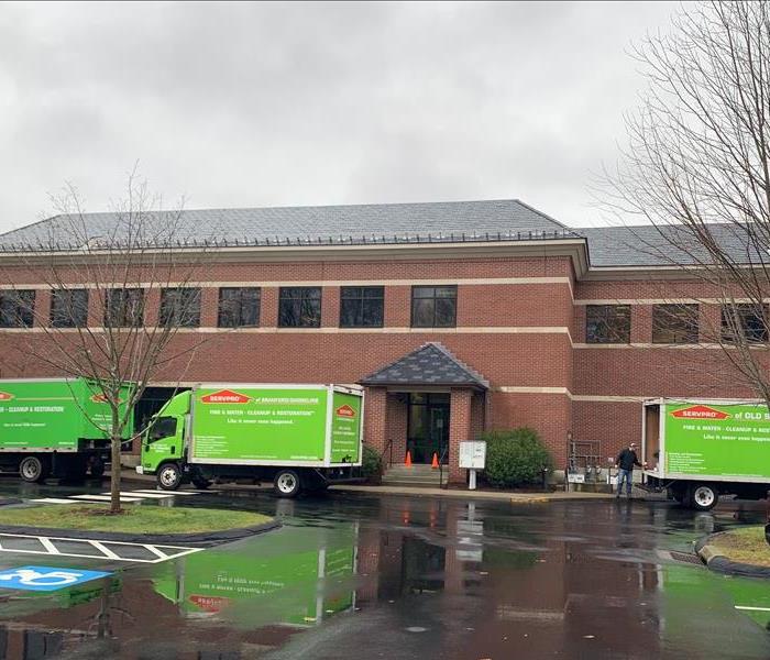 Large office building with SERVPRO trucks outside for water damage cleanup and repair.