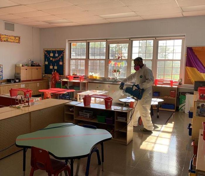 worker in full PPE disinfecting meriden classroom by fogging a sanitizer into air